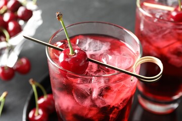 Tasty cherry soda with ice cubes and berries in glasses on grey table, closeup