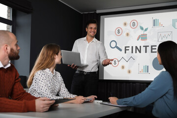 Business trainer giving lecture using video projector in conference room. Fintech word and...