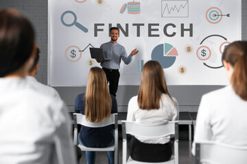 Business trainer giving lecture using video projector in conference room. Fintech word and...