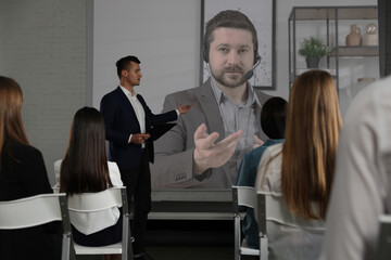 Group of people participating in business conference indoors. Speaker on projection screen