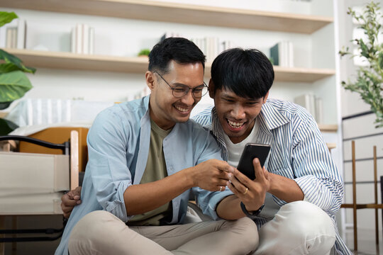 Gay couple sharing laughter while exploring their smartphone