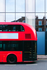 Classic red double-decker bus parked on london street with blank billboard