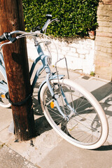 Light blue vintage bicycle leaning against wooden pole on sunny day