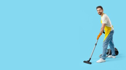 Handsome man in apron using vacuum cleaner on blue background with space for text