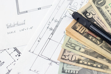 Big amount of US dollars money bills with pen and planning blueprints of residential building...