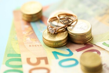 European union Euro money bills and coins with wedding rings on blue table