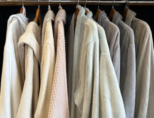 Soft, cozy bathrobes in pastel light colors hanging neatly in a closet. The robes evoke a sense of...