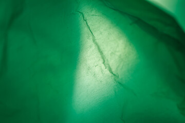 Extreme close up of green empty plastic bag background. The plastic surface is wrinkly and tattered...