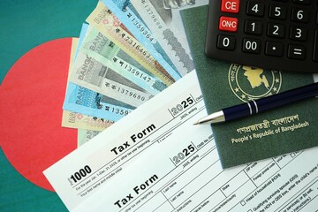 Bangladeshi taka money bills lies on table with pen, calculator, passport and tax forms