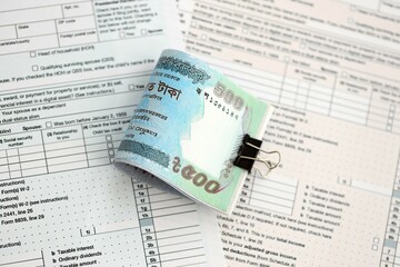 Bangladeshi taka money bills in big amount lies on table with tax forms close up