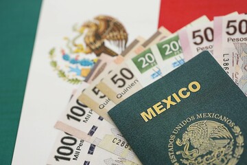 Mexican pesos money bills in big amount and passport lies on Mexico flag close up