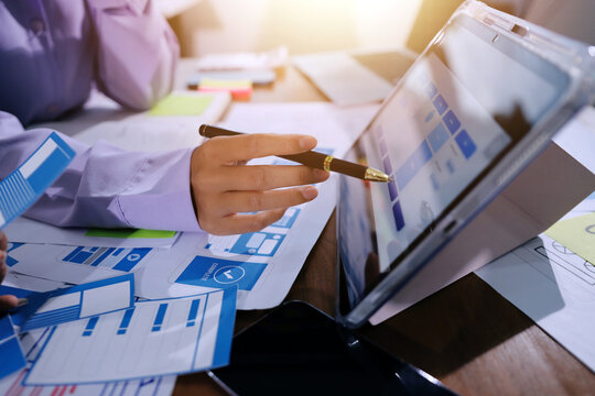 Close up ux developer and ui designer brainstorming about mobile app interface wireframe design on table with customer breif and color code at modern office.Creative digital development agency.