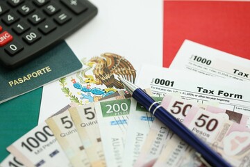 Mexican pesos money bills in big amount lies on table with pen, calculator, passport and tax forms