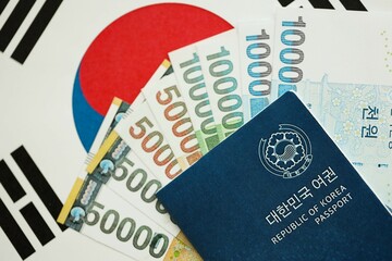 South Korean won money bills in big amount and passport lies on South Korea flag