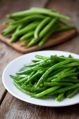 Freshly harvested green beans arranged on a white plate, with more beans on a wooden cutting board in the background