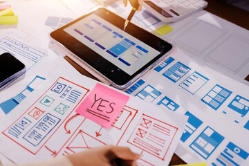 Fototapeta premium Close up ux developer and ui designer brainstorming about mobile app interface wireframe design on table with customer breif and color code at modern office.Creative digital development agency.