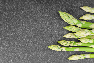 Bunch of raw fresh green asparagus stalks macro, close up on black textured background with copy...