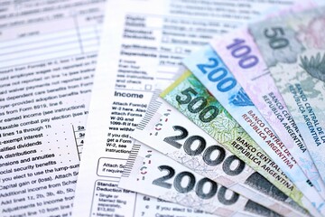 Argentine pesos money bills in big amount lies on table with pen and tax forms close up