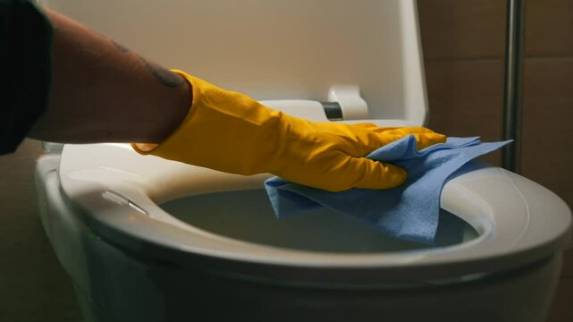 The process of washing a dirty toilet using rubber gloves.
Disinfection and cleaning of the toilet.
The housekeeper washes and cleans the toilet with a rag and detergent.
Disinfection, cleaning