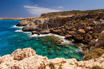 Rocky Coastline with Turquoise Water in Cyprus, Scenic view of a rugged rocky shoreline and crystal-clear turquoise sea on a sunny day. summer travel , summer travel , hot summer 