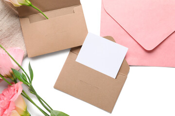 Composition with blank card, envelopes and beautiful eustoma flowers on white background, closeup