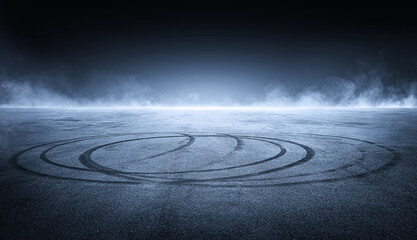 Dark empty asphalt street with visible tire marks, with a subtle mist or smoke drifting through the...