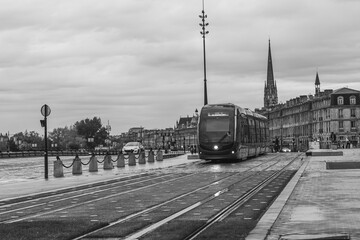 Modern tram passing through bordeaux cityscape in black and white