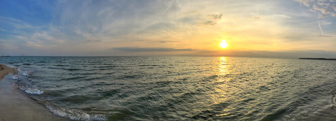 Panoramic beach sunset view with calm ocean waters and golden hues