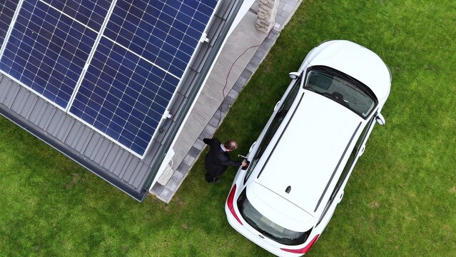 Electric car being charged at home with solar panel installed on house rooftop - Powered by Adobe