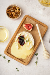 Wooden board of tasty baked Camembert cheese on light background
