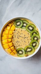 A bowl of smoothie topped with mango cubes, kiwi slices, and chia seeds. The vibrant colors create an appealing and healthy breakfast option.