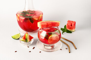 Glass and bottle of fresh watermelon lemonade with lime on white background