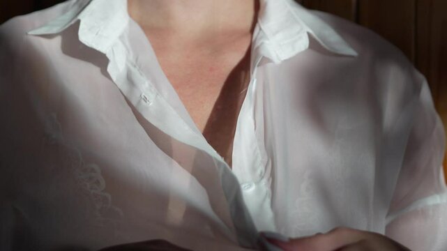 Sheer fabric hands adjusting white shirt close up