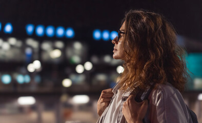 Portrait of a serious young woman wearing glasses in profile against the backdrop of night city lights