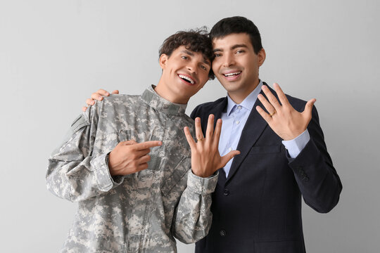 Young soldier with his husband on light background