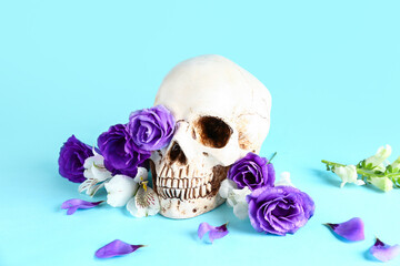 Human skull with beautiful flowers on blue background
