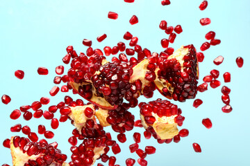 Flying fresh pomegranates with seeds on blue background