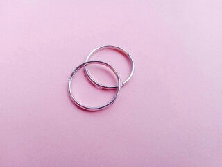 two wedding rings. a pair of silver rings isolated on a pink background. silver fashion jewelry