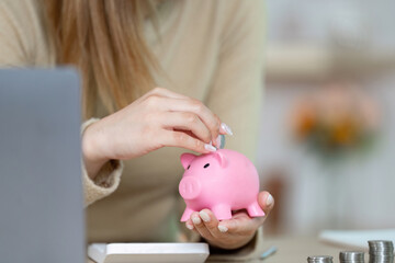 Saving Money and Financial Responsibility. Woman adding coins to pink piggy bank.