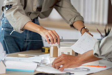 Architectural Design Collaboration. Professionals working on a building model with tools and...