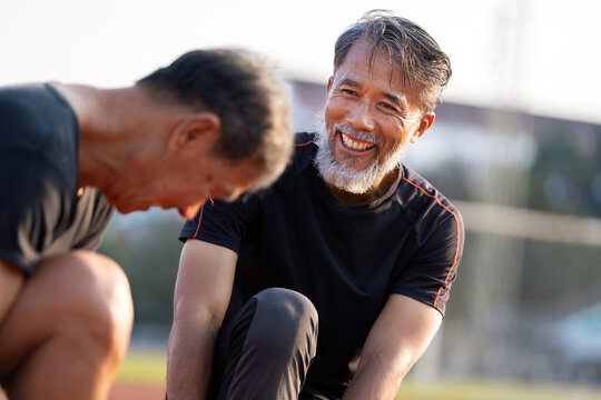 Senior Men Engaging in Fitness Activities. Two older men laughing and exercising together outdoors. - Powered by Adobe