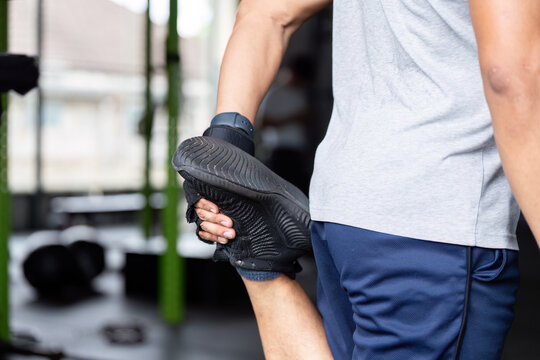 Fitness Stretching Routine. Man stretching leg muscles before workout at gym.