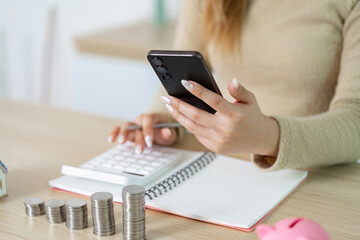 Digital Finance Management. Woman using smartphone while budgeting with coins.
