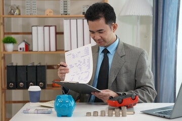 Businessman is placing coins next to toy car, which represents saving money to buy a car. Finance...