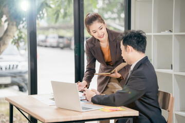 Two Asian businessmen discussing charts and graphs showing the results of successful teamwork. Using chart pads and tablets at work
