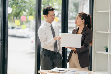Two Asian businessmen discussing charts and graphs showing the results of successful teamwork. Using chart pads and tablets at work