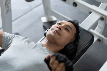 Weightlifting and Focus. Man lifting weights on bench press in gym.