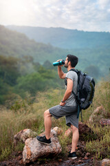 Man Hiker Taking Break and Drinking Water While Enjoying Scenic Mountain View During Summer Outdoor Adventure Journey