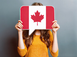 The vibrant red and white of the Canadian flag contrasts with the muted gray background.