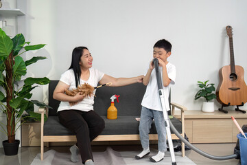 Obraz premium Cleaning and Family Interaction. A mother and son share a light moment while cleaning the living room.